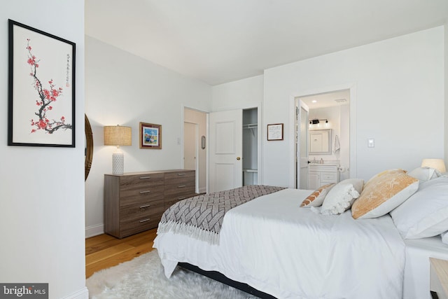 bedroom with ensuite bath, light hardwood / wood-style floors, and a closet