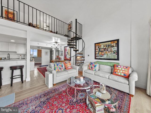 living room featuring sink, light wood-type flooring, and a high ceiling