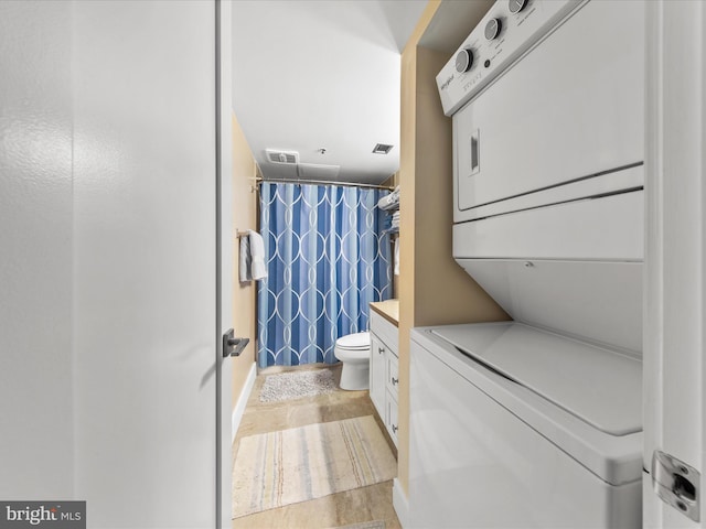 bathroom featuring stacked washer and dryer, vanity, walk in shower, and toilet