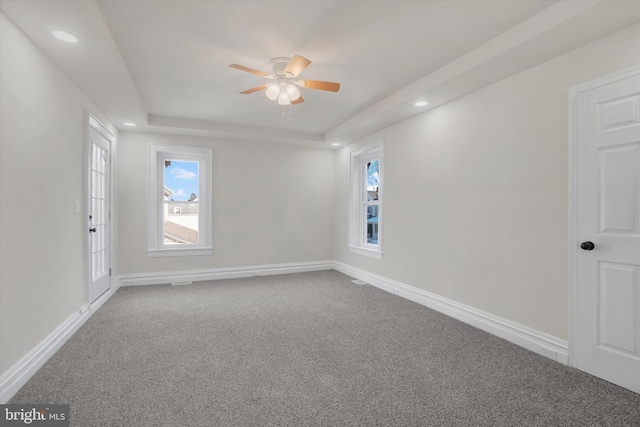 carpeted empty room featuring a raised ceiling and ceiling fan