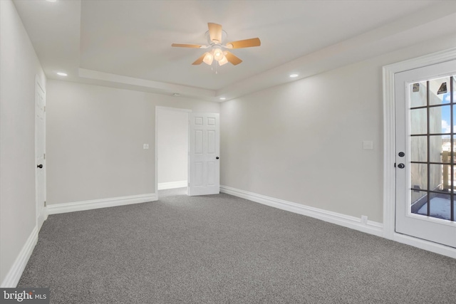 carpeted spare room featuring ceiling fan and a tray ceiling