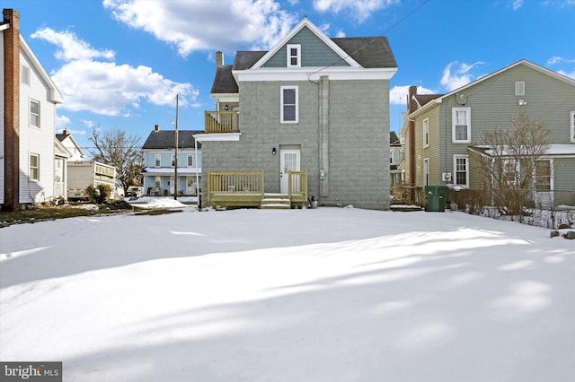 snow covered rear of property with a balcony