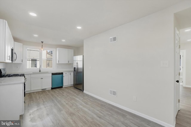 kitchen with sink, light hardwood / wood-style flooring, appliances with stainless steel finishes, pendant lighting, and white cabinets