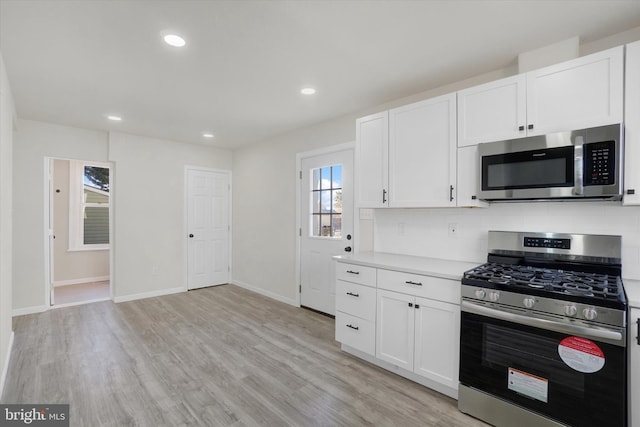 kitchen featuring appliances with stainless steel finishes, backsplash, white cabinets, and light wood-type flooring