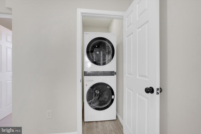 laundry room with stacked washer / drying machine and light hardwood / wood-style flooring