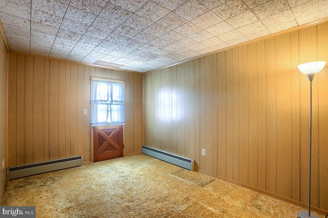 spare room featuring a baseboard radiator, wooden walls, and carpet