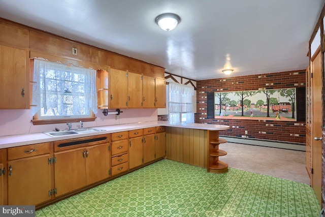 kitchen with baseboard heating, brick wall, kitchen peninsula, and sink