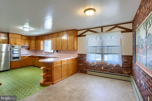 kitchen featuring stainless steel appliances, brick wall, and a baseboard heating unit