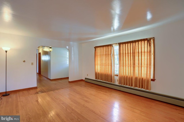 unfurnished room featuring a baseboard heating unit and wood-type flooring