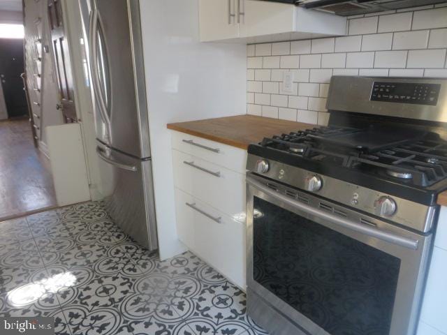 kitchen with white cabinetry, decorative backsplash, stainless steel appliances, and wooden counters