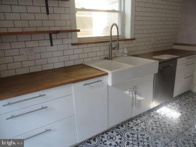 kitchen featuring tasteful backsplash, butcher block counters, sink, and white cabinets