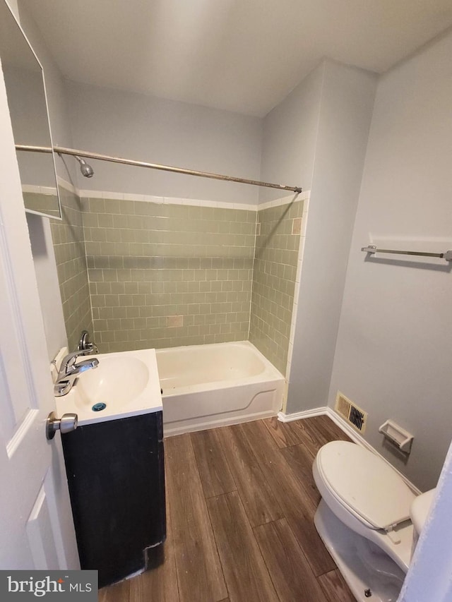 full bathroom featuring vanity, tiled shower / bath combo, wood-type flooring, and toilet