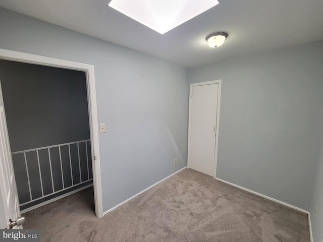 empty room featuring a skylight and carpet floors