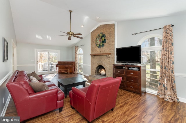 living room featuring ceiling fan, lofted ceiling, wood-type flooring, and a brick fireplace