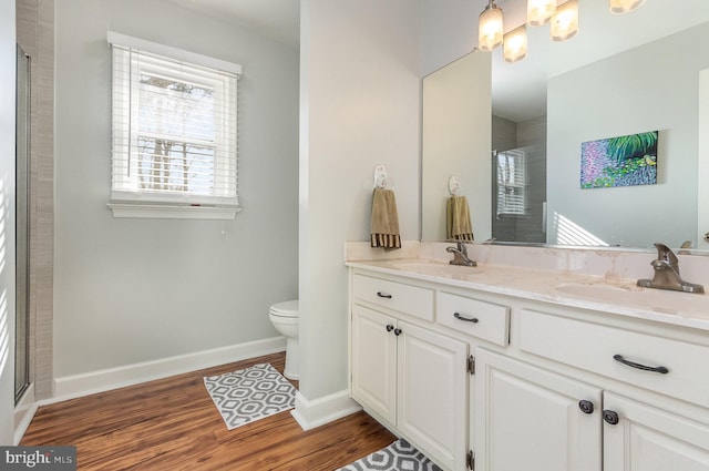 bathroom featuring wood-type flooring, toilet, a shower with door, and vanity