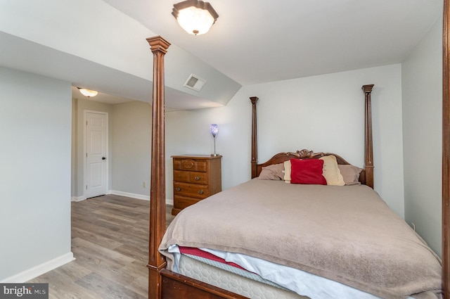 bedroom featuring vaulted ceiling, light hardwood / wood-style floors, and ornate columns