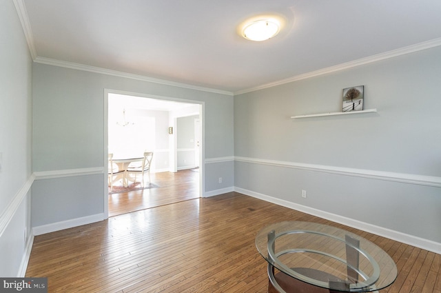 unfurnished room with hardwood / wood-style floors, crown molding, and a chandelier