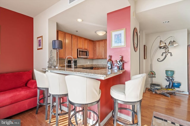 105 Christina Landing Dr Unit 905, Wilmington, DE 19801 - kitchen featuring sink, hardwood / wood-style flooring, a kitchen breakfast bar, light stone counters, and kitchen peninsula