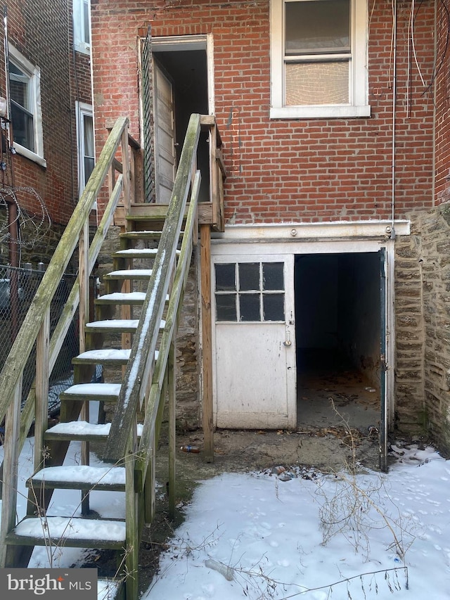 snow covered property entrance with brick siding