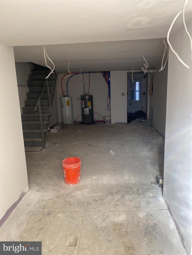 unfinished basement with stairway and electric water heater