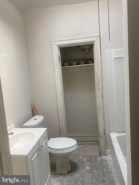 bathroom featuring toilet, a tub, and vanity