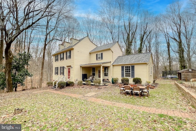 rear view of property with a trampoline, a lawn, and a patio area