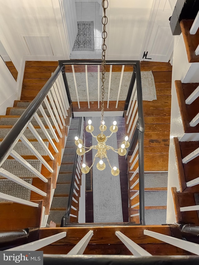 stairway featuring hardwood / wood-style flooring and a notable chandelier