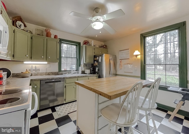 kitchen with black dishwasher, sink, stainless steel refrigerator, and green cabinetry