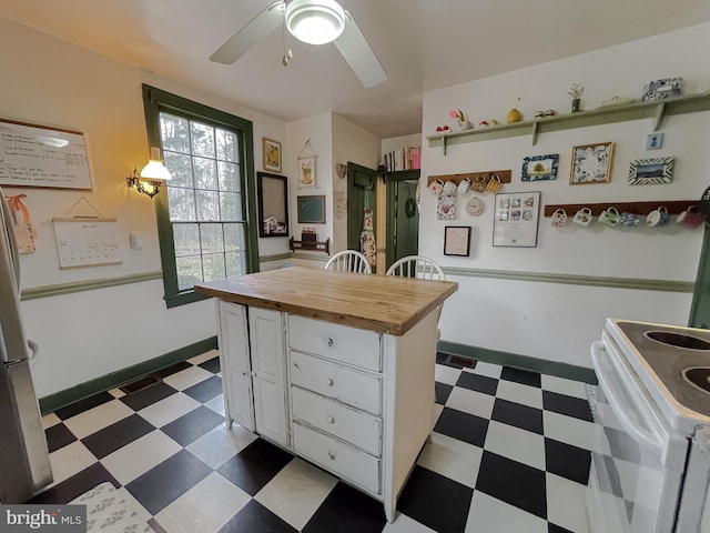 kitchen with butcher block countertops, ceiling fan, white range with electric cooktop, a center island, and white cabinets