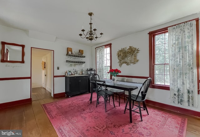 dining room featuring dark wood-type flooring, plenty of natural light, and an inviting chandelier