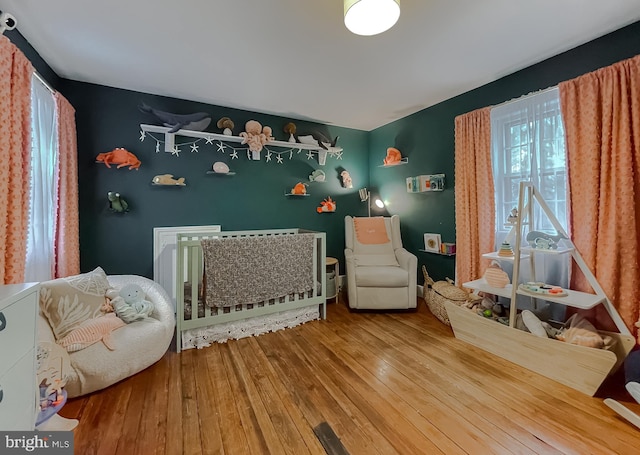 bedroom featuring a nursery area and wood-type flooring