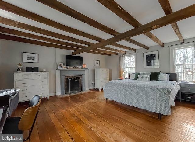 bedroom featuring hardwood / wood-style flooring, a fireplace, and beamed ceiling