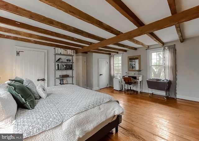 bedroom with hardwood / wood-style flooring, radiator heating unit, and beamed ceiling