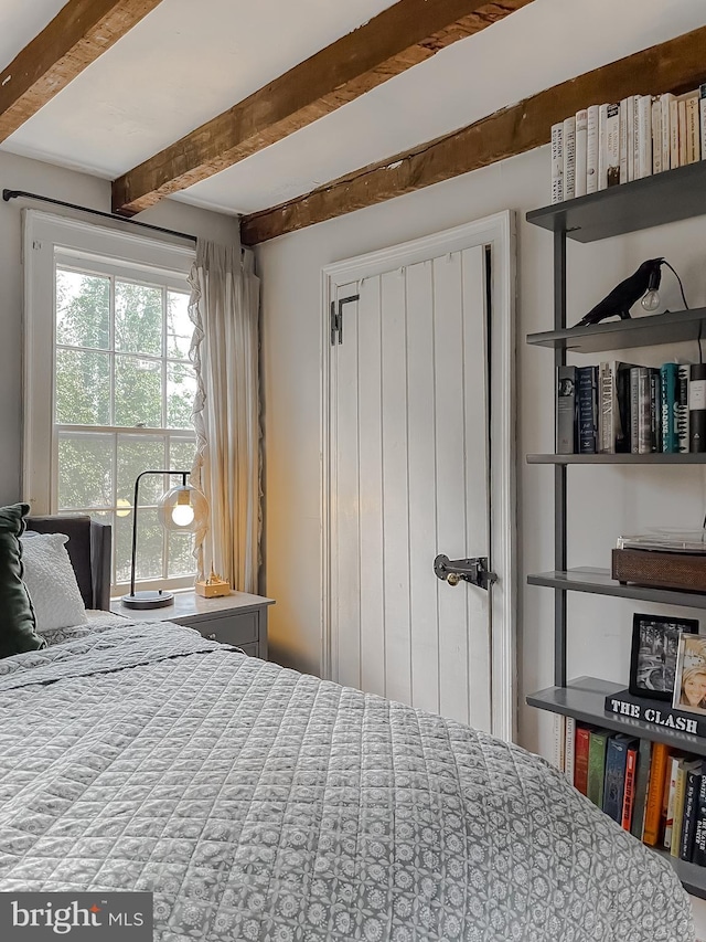 bedroom with beamed ceiling and a closet