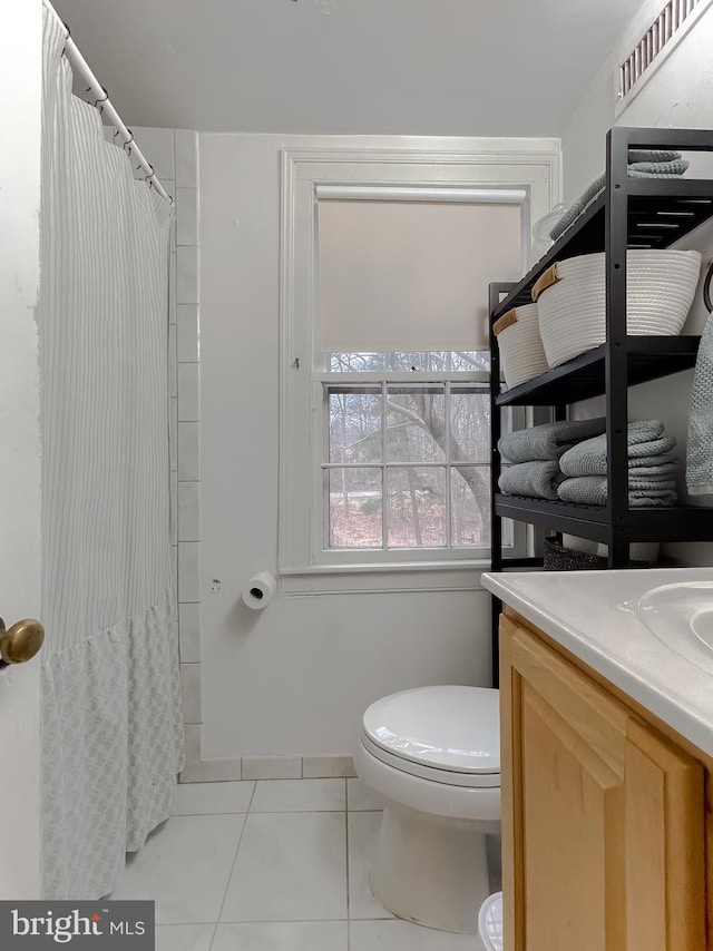 bathroom featuring tile patterned flooring, vanity, walk in shower, and toilet