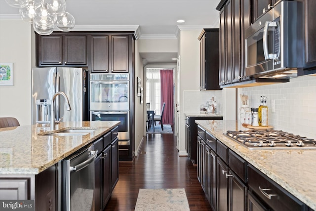 kitchen featuring light stone counters, hanging light fixtures, decorative backsplash, and stainless steel appliances