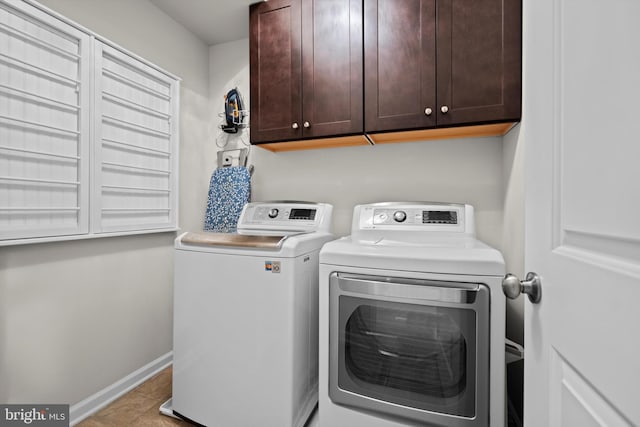 washroom featuring cabinets, washing machine and clothes dryer, and light tile patterned flooring