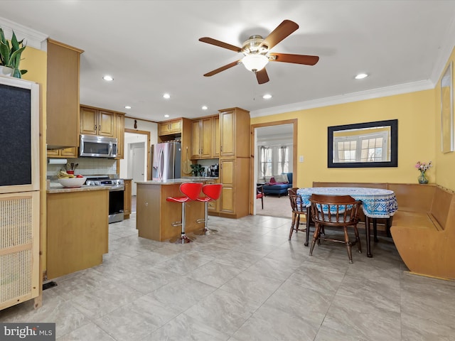 kitchen featuring a breakfast bar area, ornamental molding, appliances with stainless steel finishes, a kitchen island, and backsplash