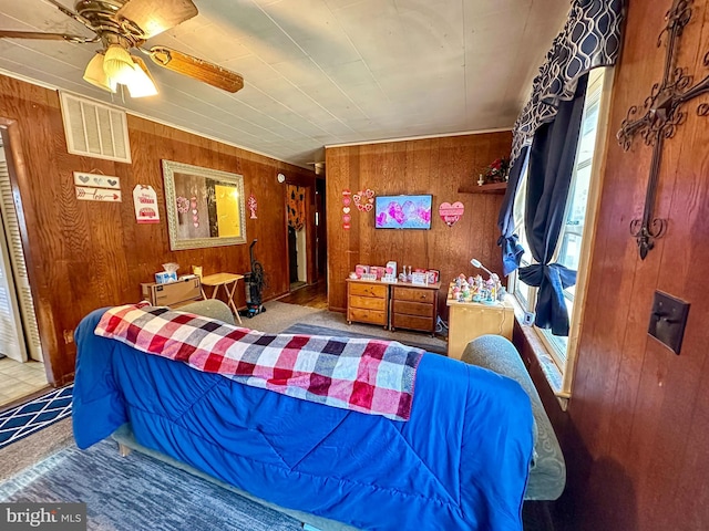 carpeted bedroom featuring ceiling fan and wooden walls