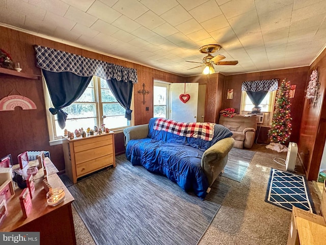 living room with ceiling fan, wooden walls, and dark carpet