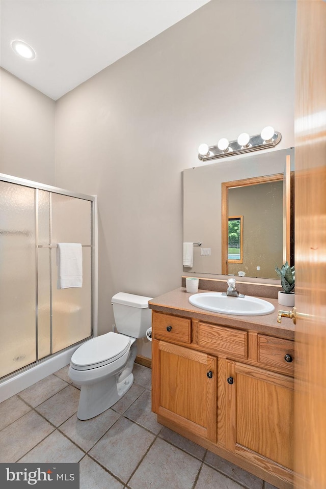 bathroom featuring a shower with door, vanity, tile patterned floors, and toilet