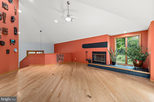 unfurnished living room with ceiling fan, wood-type flooring, a tile fireplace, and lofted ceiling