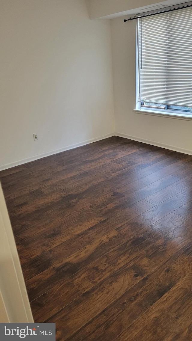 unfurnished room with dark wood-type flooring