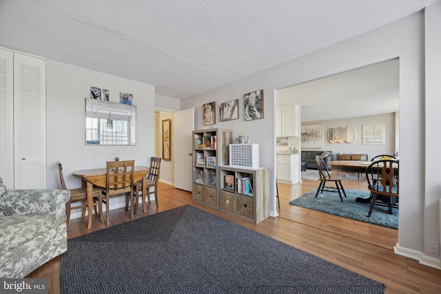 dining space with a textured ceiling, baseboards, and wood finished floors