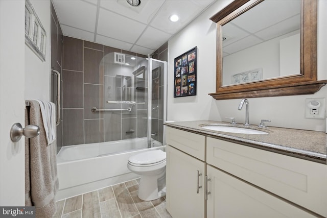 full bath with toilet, combined bath / shower with glass door, vanity, a paneled ceiling, and wood tiled floor