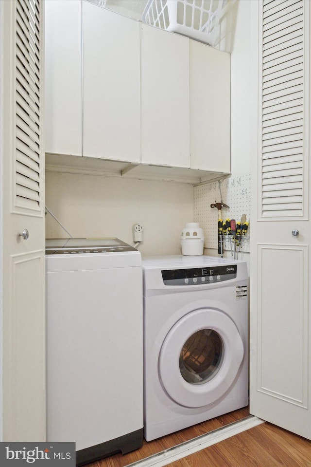 clothes washing area with cabinet space, light wood-style flooring, and washing machine and dryer