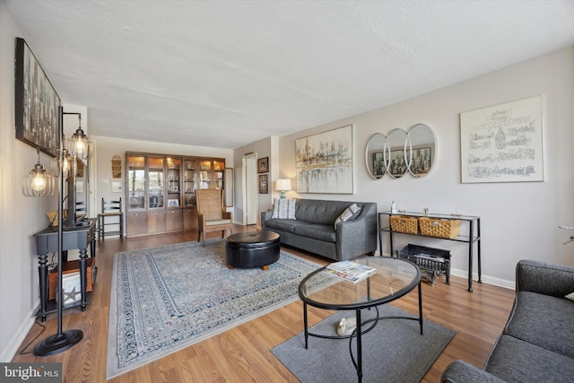 living room featuring wood finished floors, baseboards, and a textured ceiling