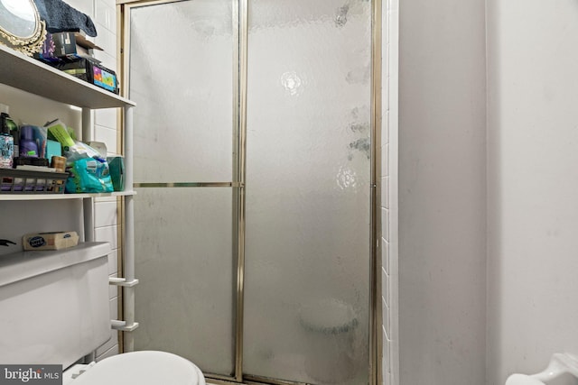 bathroom with a shower with door and toilet