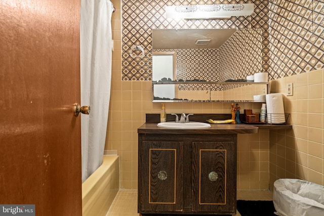 bathroom with tile walls, vanity, and shower / bath combo