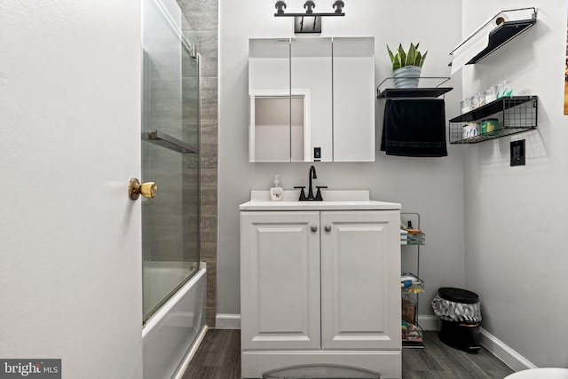 bathroom with hardwood / wood-style flooring, vanity, and shower / bath combination with glass door